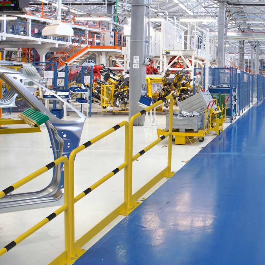 Das Bild zeigt Rammschutzbügel mit Unterfahrschutz als Geländer und Verkehrswegbegrenzung in einer Industriehalle.