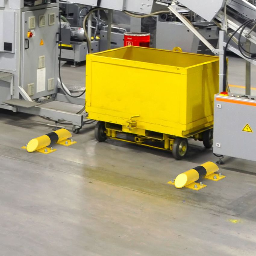 Gelb-schwarze Rammschutzbalken mit abgeschrägten Kanten sichern eine Transportstrecke in einer Produktionshalle mit Maschinen und Transportwagen.