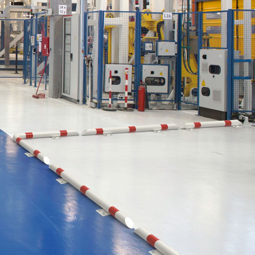 Weiß-rote Rammschutzbalken in L-Form sichern Maschinenbereich in einer Industriehalle.